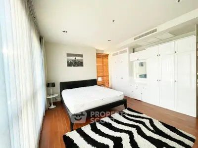 Spacious bedroom with modern decor and ample natural light in a stylish apartment.