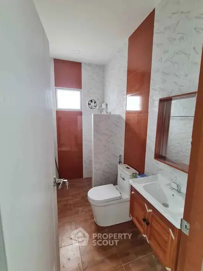Modern bathroom with sleek design and wooden vanity in a real estate property.