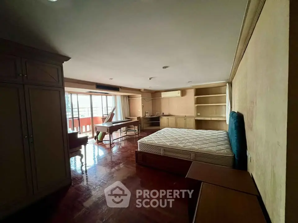 Spacious bedroom with balcony access and natural light in urban apartment