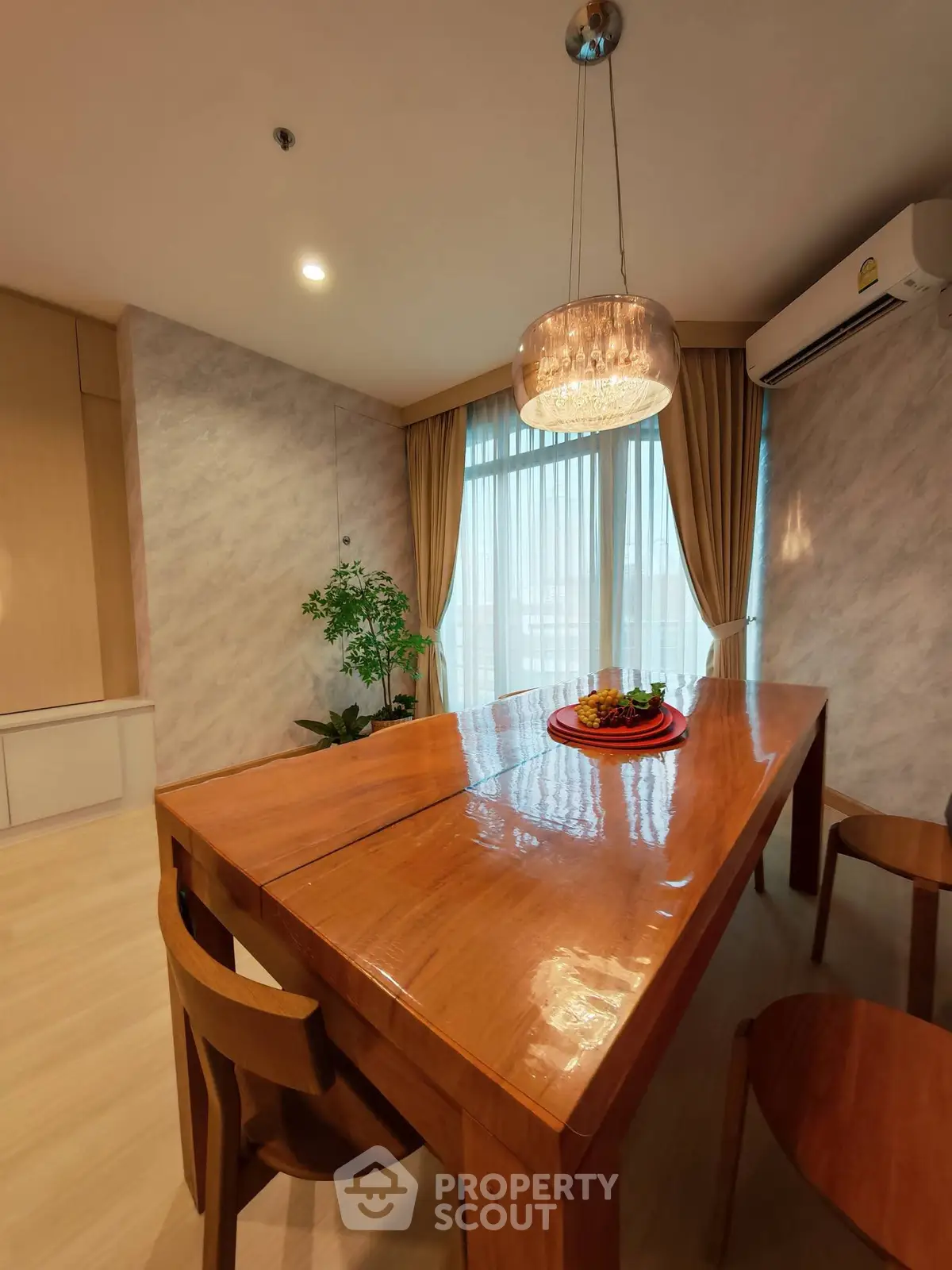 Elegant dining area with wooden table, modern lighting, and large window with curtains.