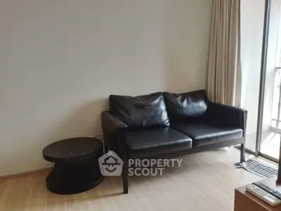 Modern living room with sleek black sofa and round side table near balcony.
