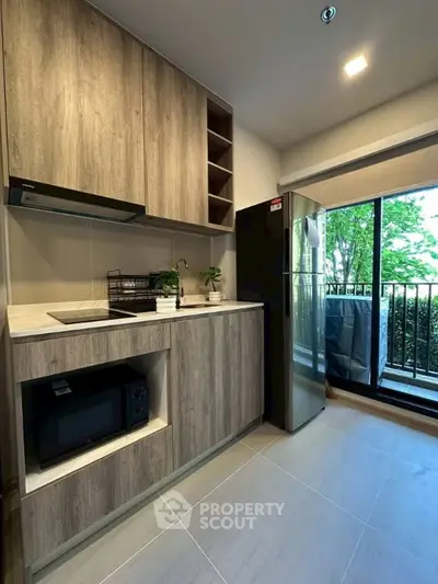 Modern kitchen with sleek cabinetry and balcony view, featuring built-in appliances and natural light.
