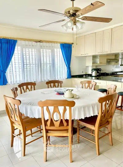 Spacious kitchen with elegant dining area and natural light, featuring wooden furniture and modern appliances.