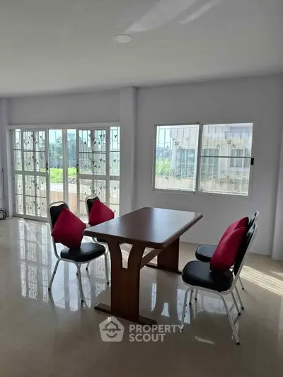 Spacious dining area with large windows and modern furniture, offering abundant natural light and a serene view.