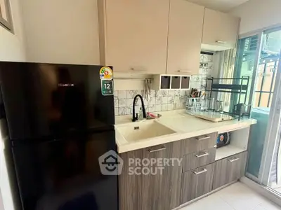 Modern kitchen with sleek cabinetry and black fridge in a compact layout