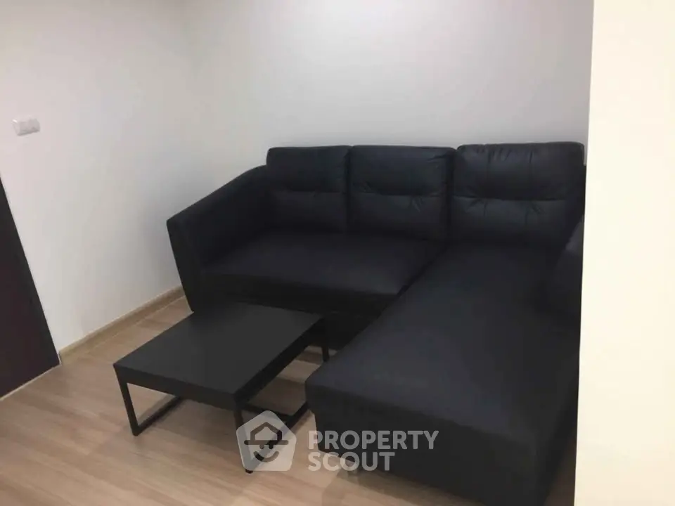 Modern minimalist living room with sleek black sofa and matching coffee table.