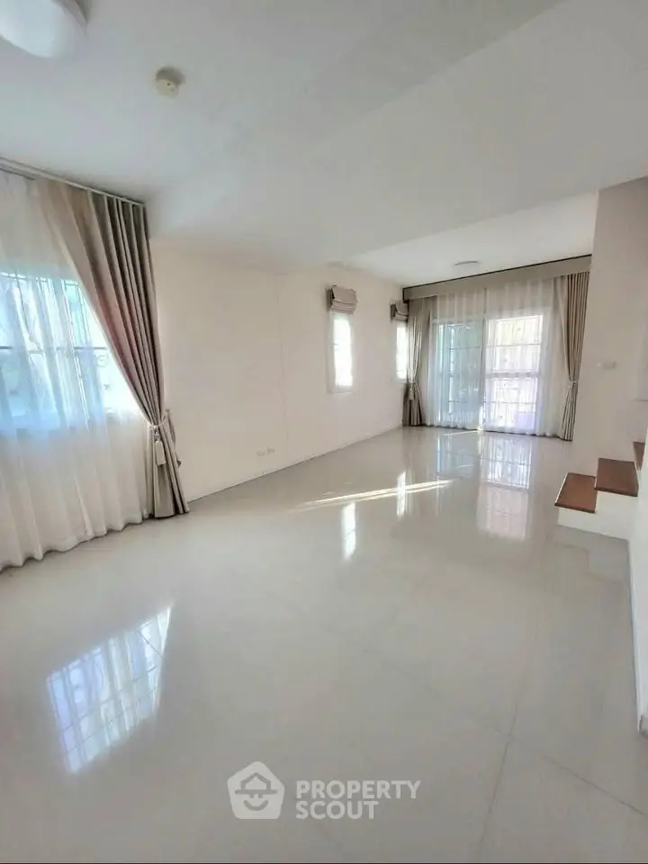 Spacious and bright living room with large windows and elegant curtains.
