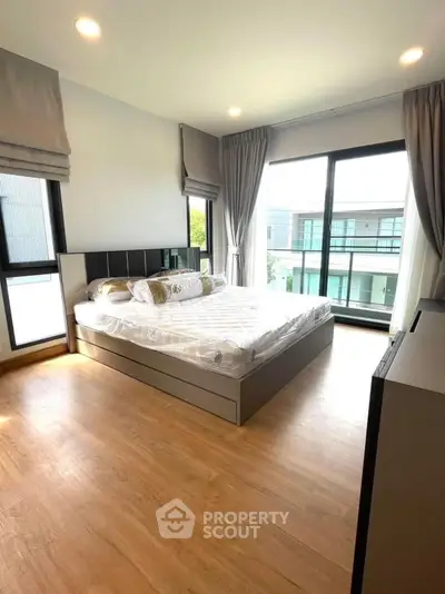 Spacious bedroom with large windows and modern decor in a contemporary home.