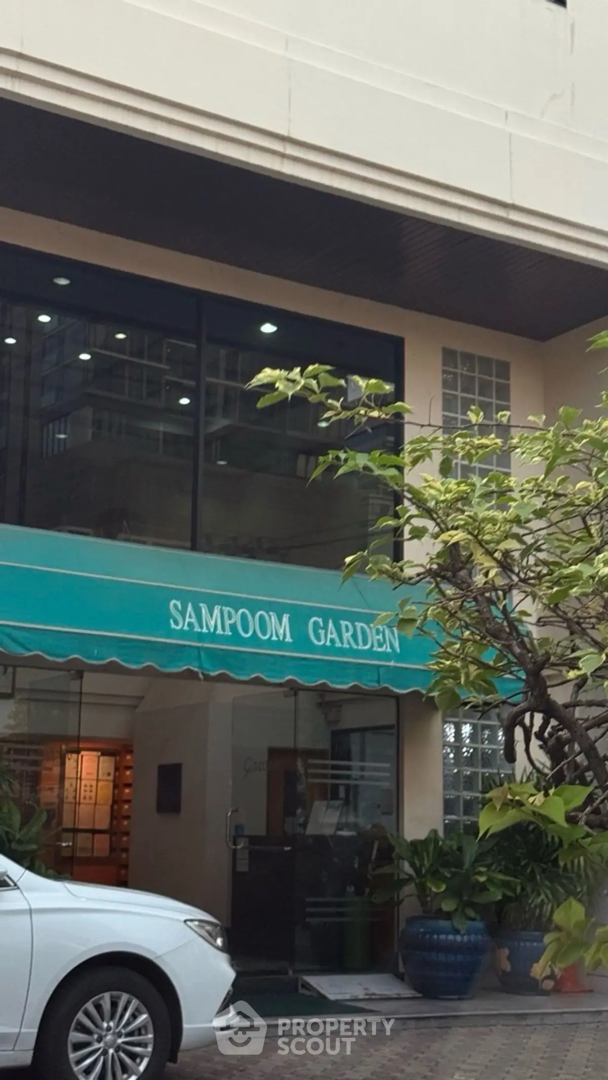 Charming entrance of Sampoom Garden with lush greenery and modern architecture.