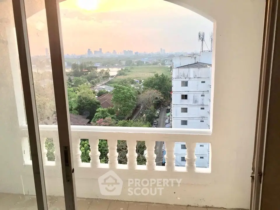 Stunning balcony view of city skyline and lush greenery at sunset.