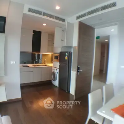 Modern kitchen with sleek appliances and wooden flooring in a stylish apartment.