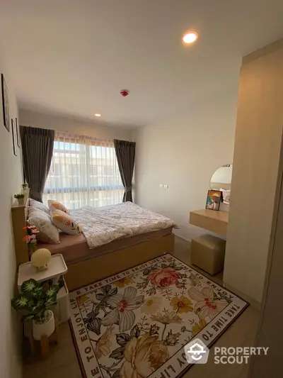 Cozy bedroom with large window and floral rug, perfect for relaxation and comfort.