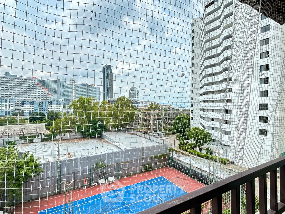 Stunning cityscape view from a high-rise balcony overlooking tennis courts and modern architecture.