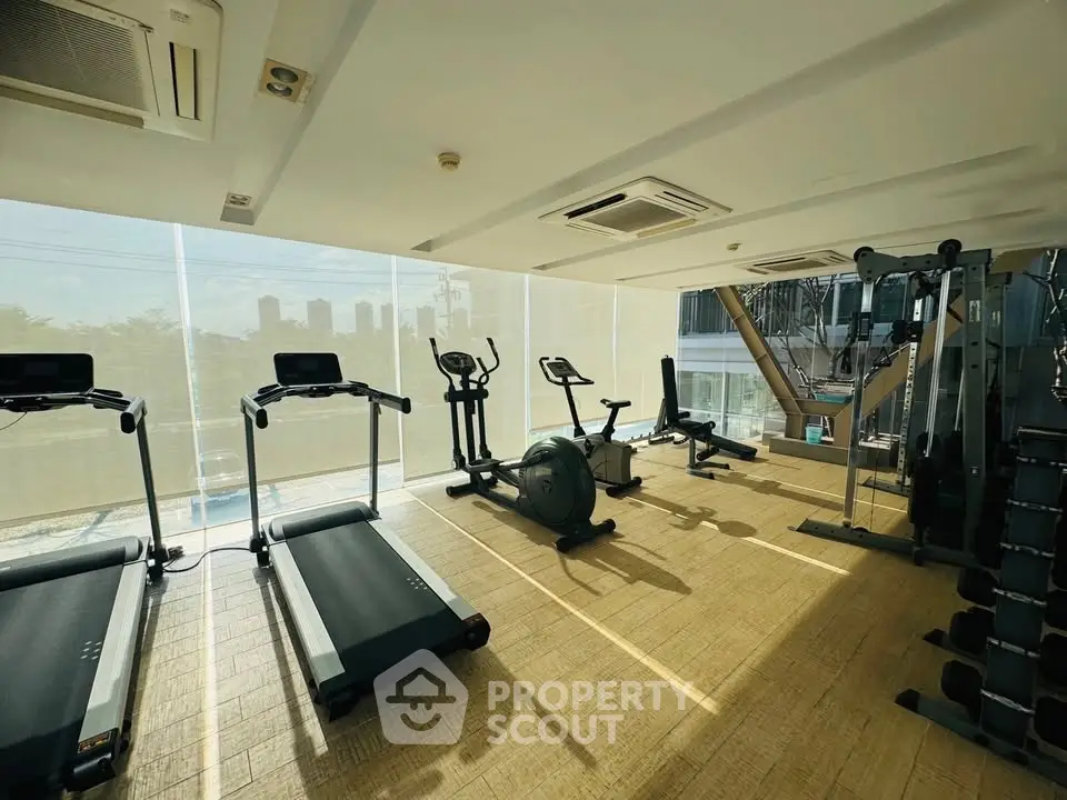 Modern gym with cardio equipment and city view, perfect for fitness enthusiasts.