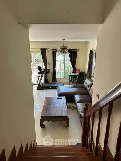 Spacious living room with modern furniture and treadmill, perfect for relaxation and fitness.