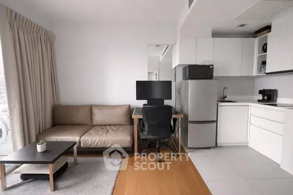 Modern living room with sleek kitchen, cozy sofa, and workspace in open layout apartment.