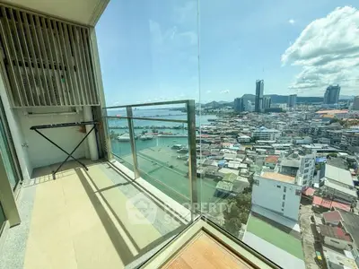 Stunning city and ocean view from high-rise balcony with glass railing.