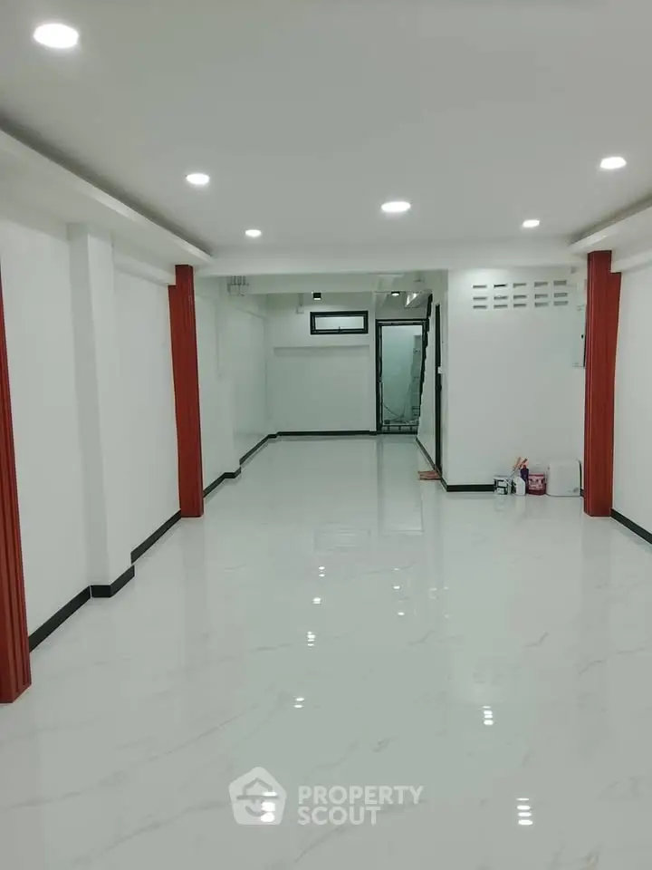 Spacious modern interior with glossy white flooring and recessed lighting, ideal for versatile living or office space.