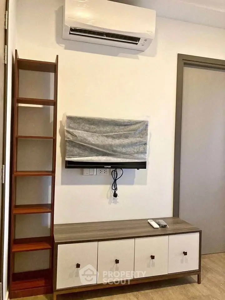 Modern living room with air conditioner and stylish TV setup, featuring sleek wooden furniture and minimalist design.