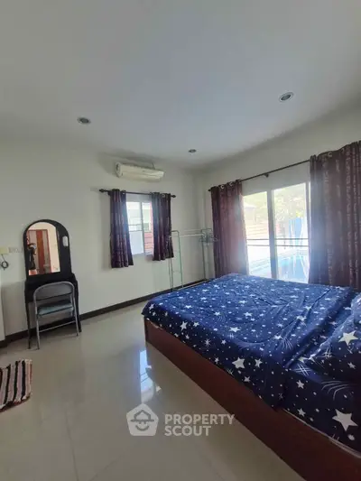 Spacious bedroom with starry bedding and natural light from large windows.