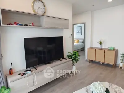 Modern living room with sleek furniture and large TV, showcasing stylish decor and open layout.