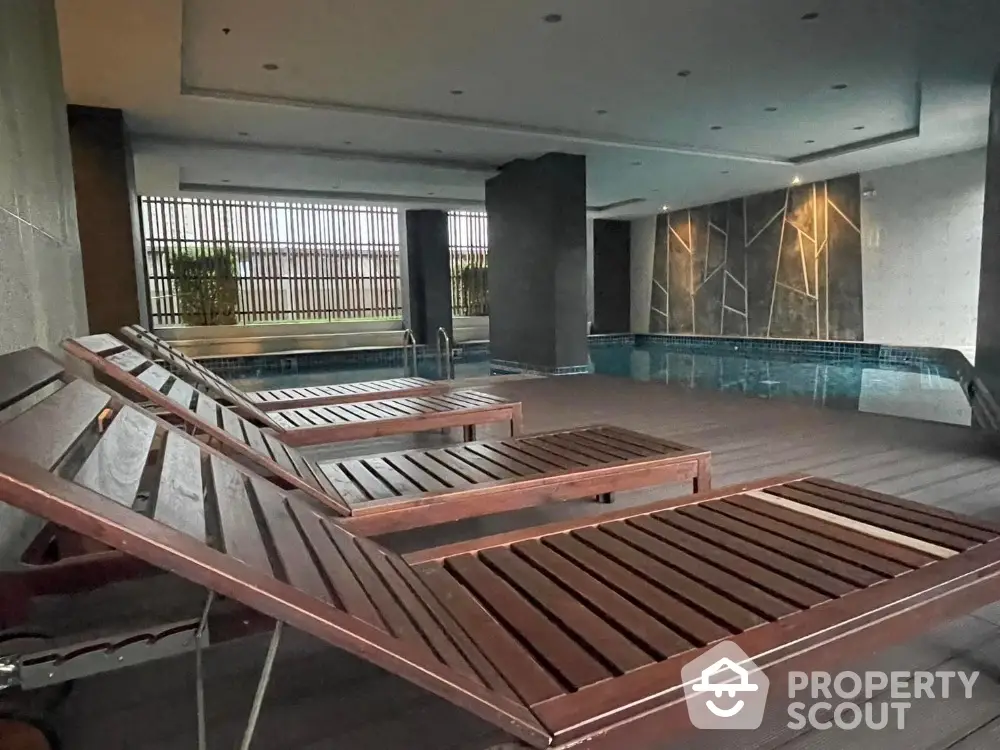 Luxurious indoor pool area with stylish wooden loungers and modern design