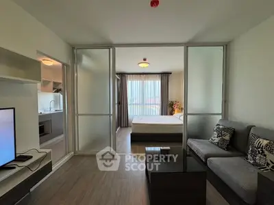 Modern apartment interior with open living room and bedroom layout, featuring sleek furniture and natural light.
