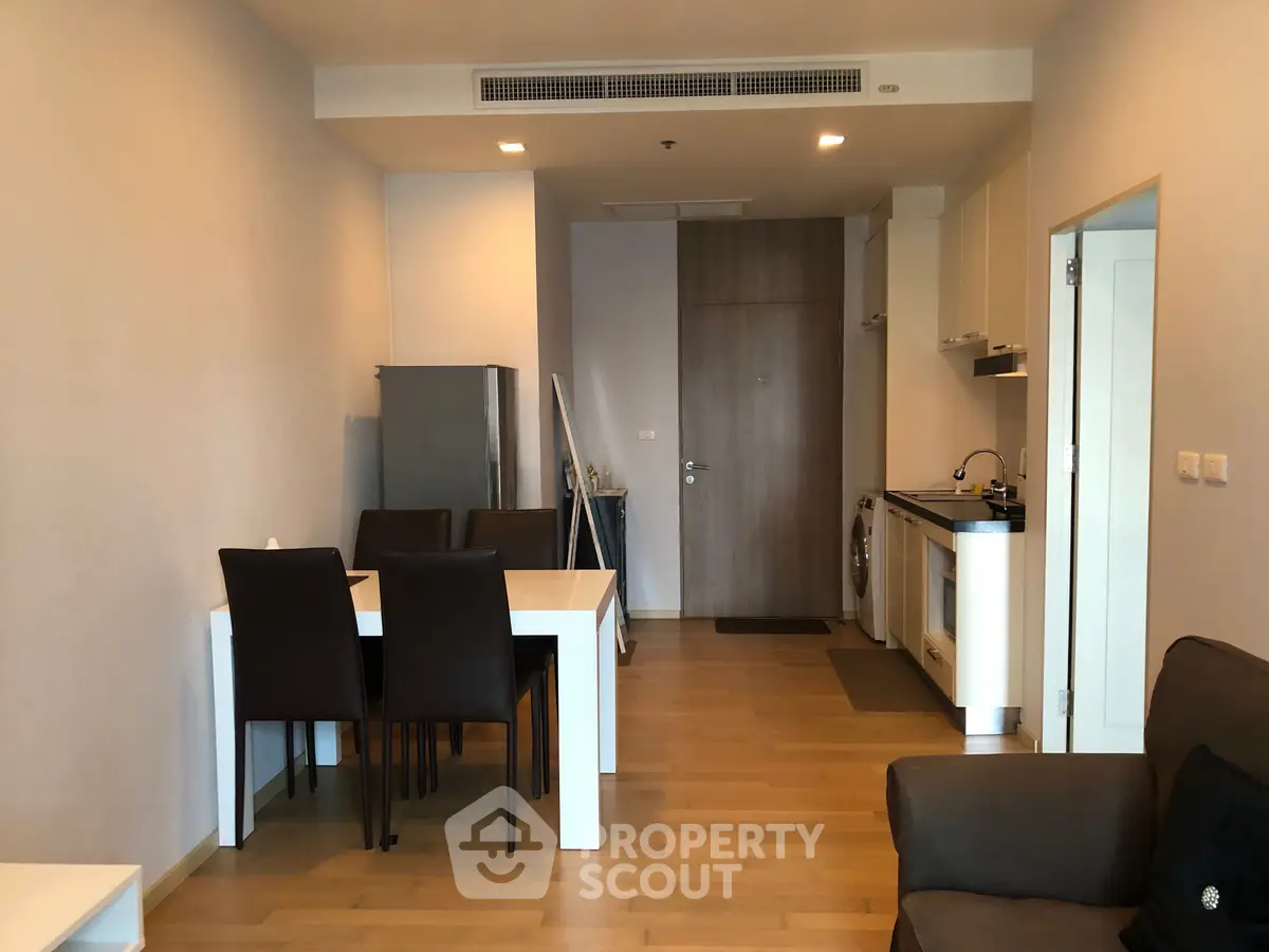 Modern open-plan living room with dining area and compact kitchen in a stylish apartment.