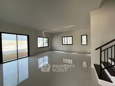 Spacious modern living room with large windows and sleek staircase.