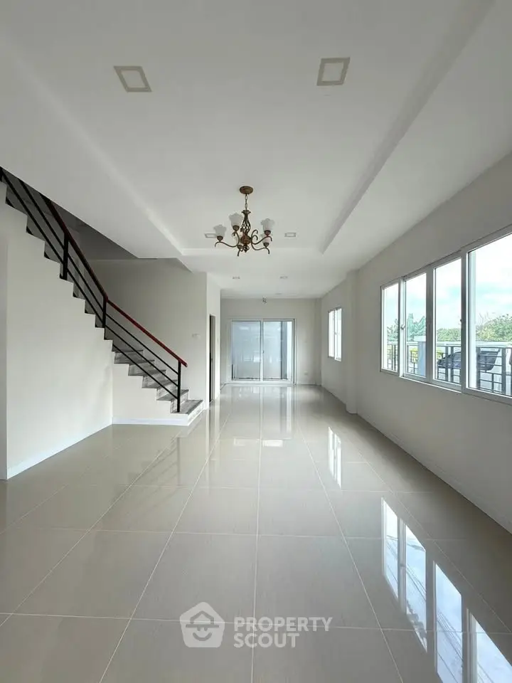 Spacious modern living room with elegant staircase and large windows