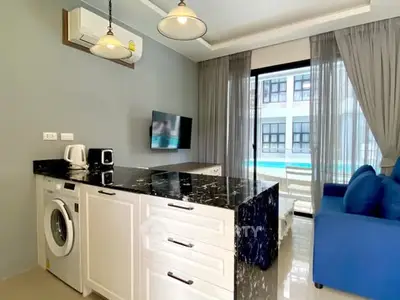 Modern living room with pool view, featuring stylish furniture and built-in appliances.