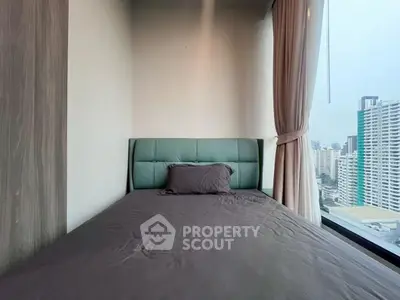 Cozy bedroom with city view, featuring a modern bed and large window for natural light.