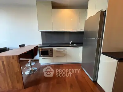 Modern kitchen with sleek cabinetry and built-in appliances, featuring a stylish breakfast bar and wooden flooring.