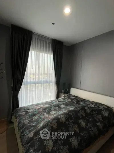 Cozy bedroom with elegant dark curtains and floral bedding, perfect for relaxation.