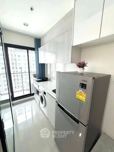 Modern kitchen with sleek appliances and large window view in a stylish apartment.
