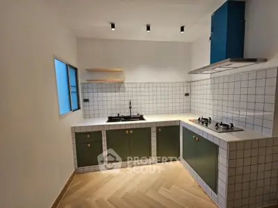Modern kitchen with green cabinets, gas stove, and stylish tile backsplash.