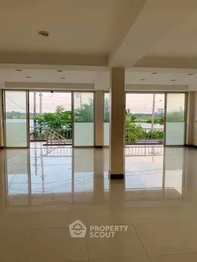 Spacious living room with large windows offering serene water views and abundant natural light.