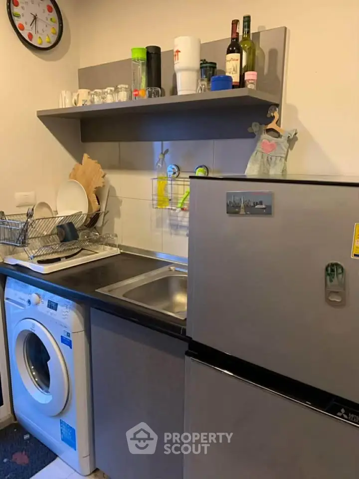 Compact kitchen with washing machine and fridge, ideal for small apartments.