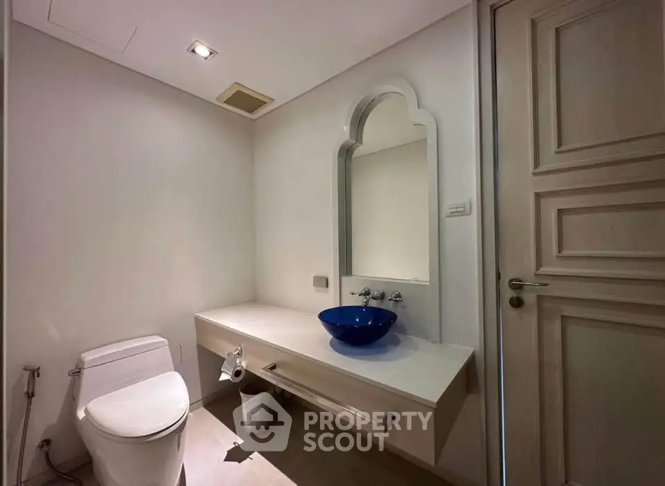 Elegant bathroom with modern fixtures and stylish blue basin in a minimalist design.