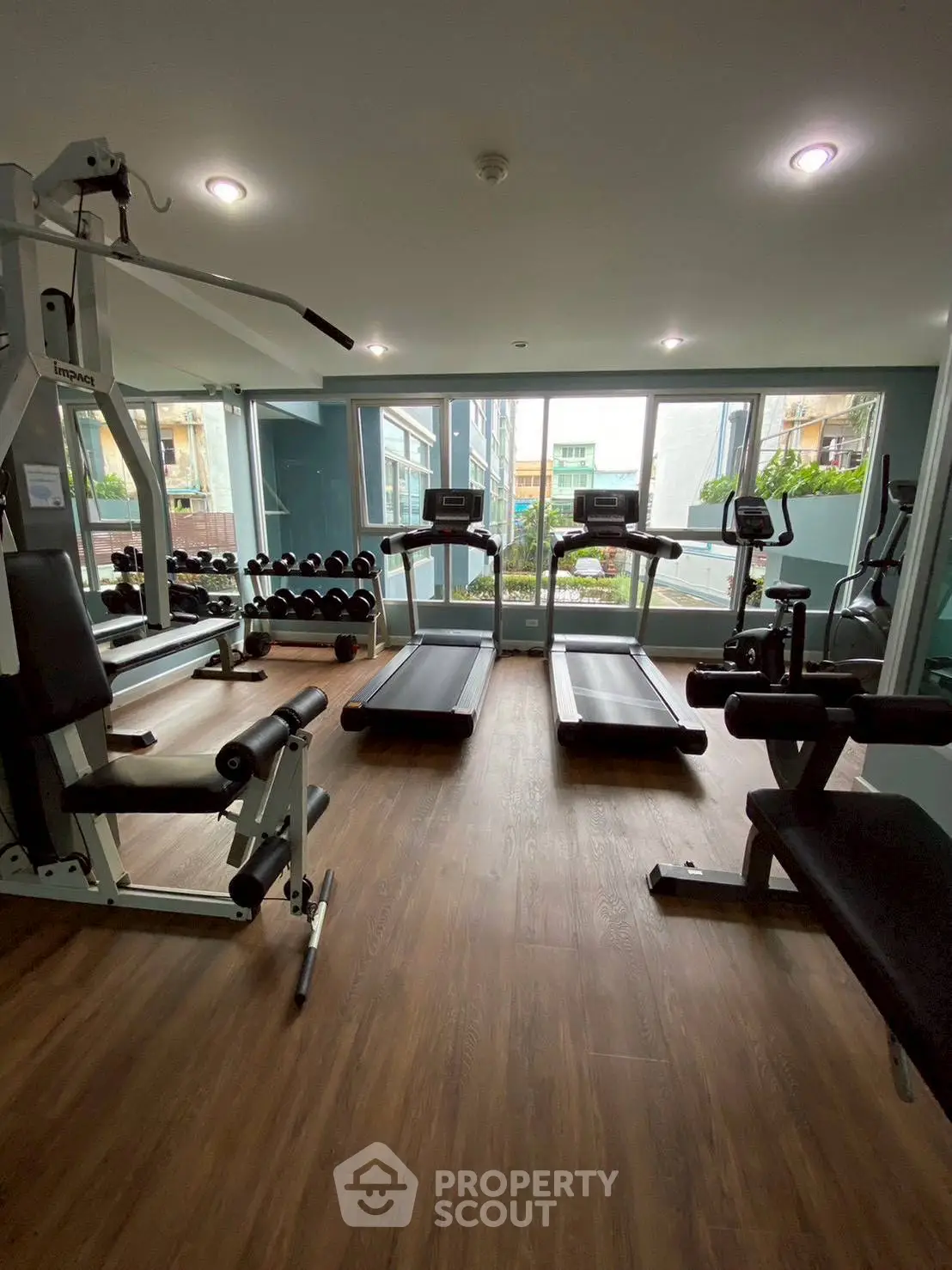 Modern gym with state-of-the-art equipment and large windows in a residential building.