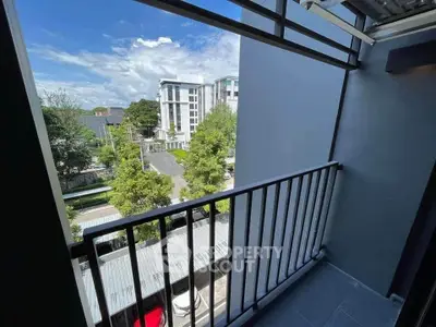 Charming balcony view overlooking modern urban landscape with lush greenery.