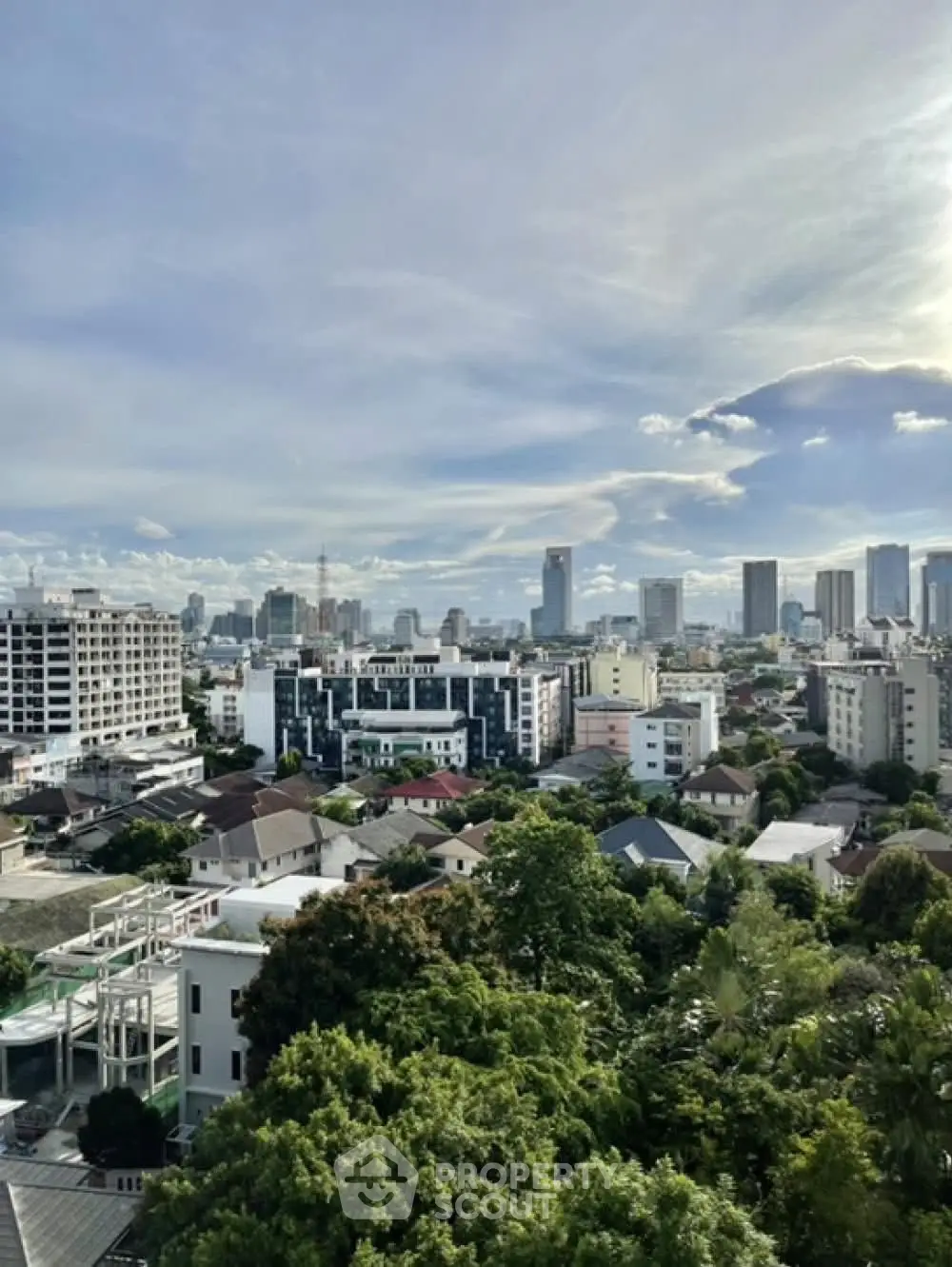 Stunning cityscape view from a high-rise building showcasing urban skyline and lush greenery.