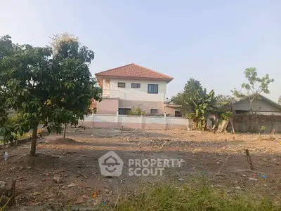 Spacious plot with potential for development, featuring a modern house and lush greenery in a serene neighborhood.