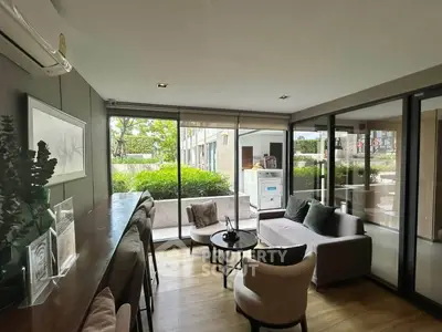Stylish living room with large windows and garden view, featuring modern furniture and elegant decor.