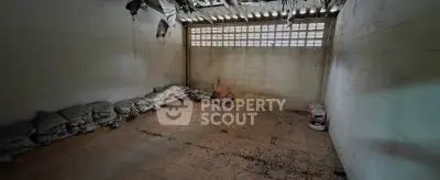 Spacious storage room with high ceiling and natural light, ideal for various uses.