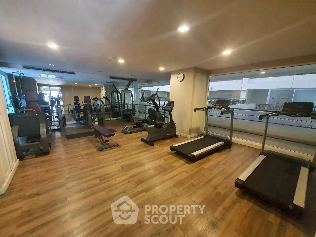 Spacious gym with modern equipment and wooden flooring in a residential building.