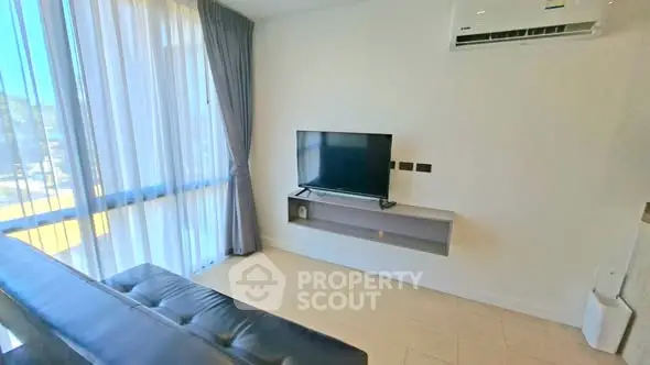 Modern living room with sleek TV setup and large window for natural light.