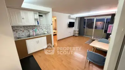 Spacious open-plan living room with modern kitchen and balcony access, featuring stylish decor and ample natural light.