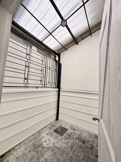 Enclosed balcony with metal grill and skylight, perfect for extra storage space.