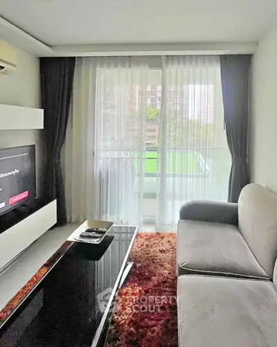 Modern living room with large window and cozy seating area in a stylish apartment.